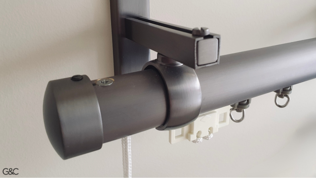 Un rail est inséré et il n'y a pas d'anneaux mais des rouleurs. Manœuvre avec cordon