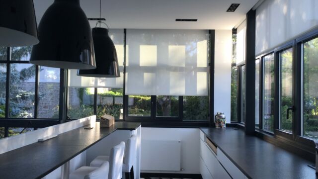 Cuisine style industriel avec des stores électriques en toile blanche créant une ambiance intime