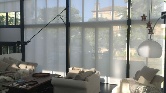 Élégants stores enrouleurs à télécommande motorisés toile blanche tamisante dans un séjour