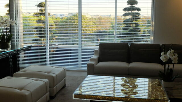 Séjour d’un appartement parisien avec des stores à lamelles blancs télécommandés pour moduler la lumière