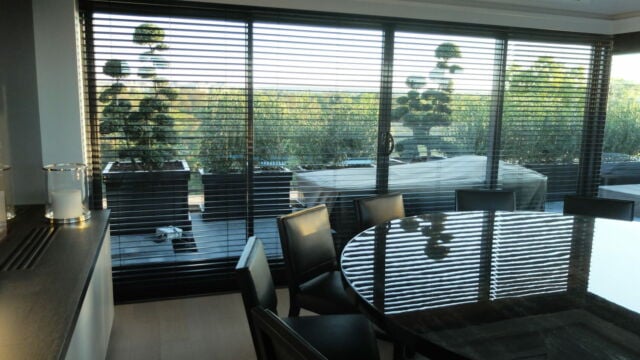 Salle à manger moderne décorée en noir avec des stores vénitiens télécommandés à lamelles blanches