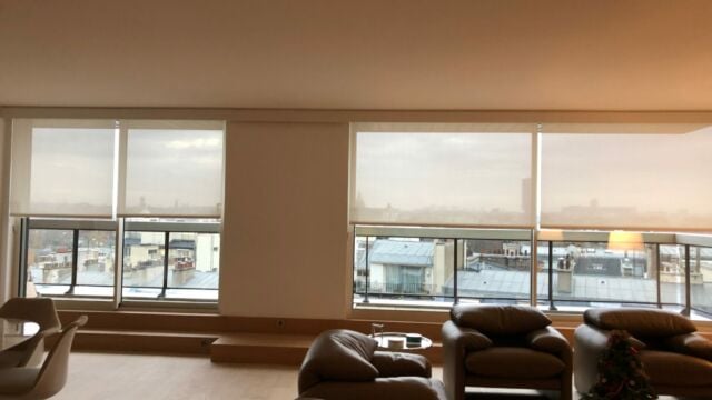 Salon parisien privé avec des stores enrouleurs sur mesure blancs motorisés à télécommande