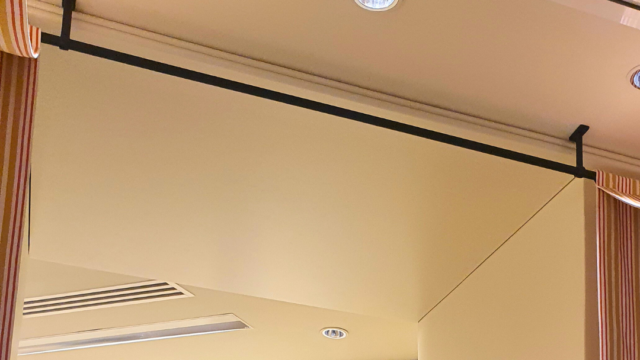 Tringles coudées avec supports plafond, couleur noir mat. Fabriquées sur mesure pour le showroom Manuel Canovas.